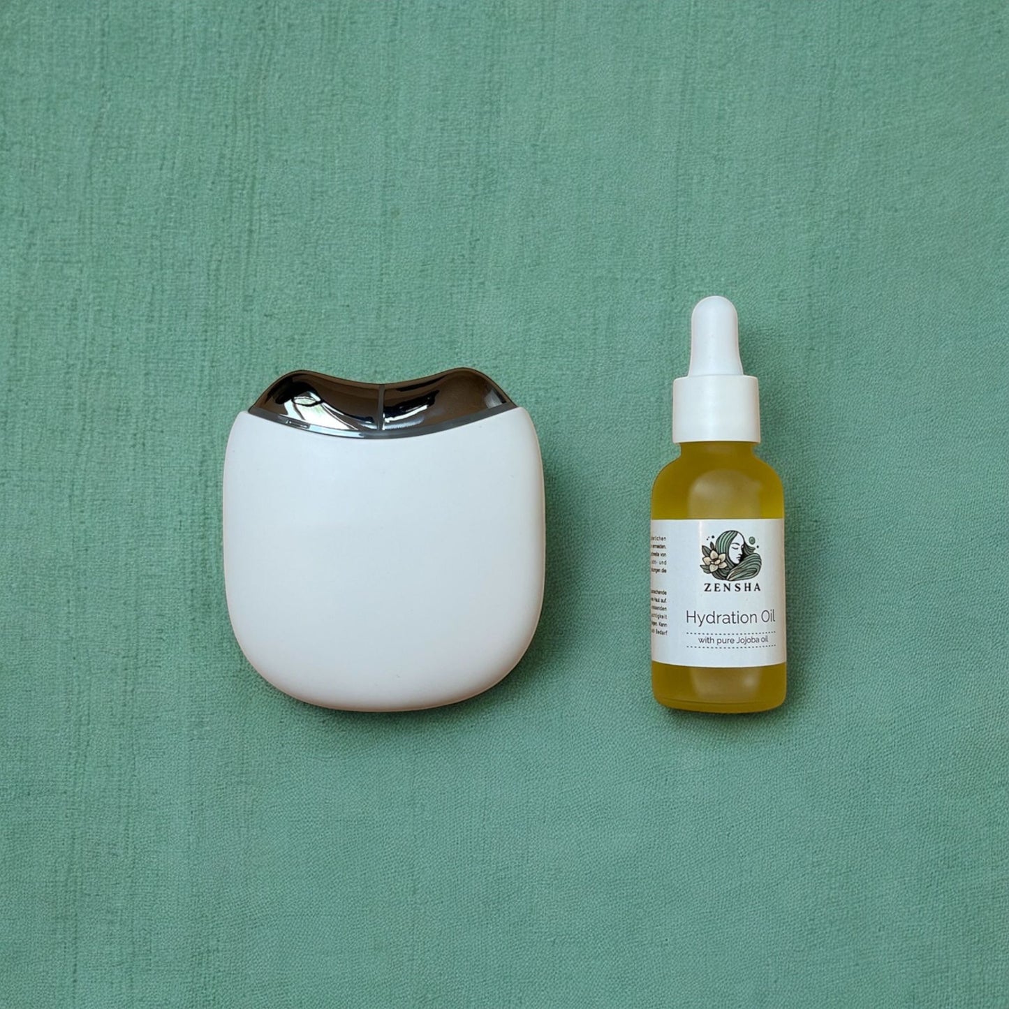 A EMS Gua Sha Product laying next to an face oil on a green background. 
